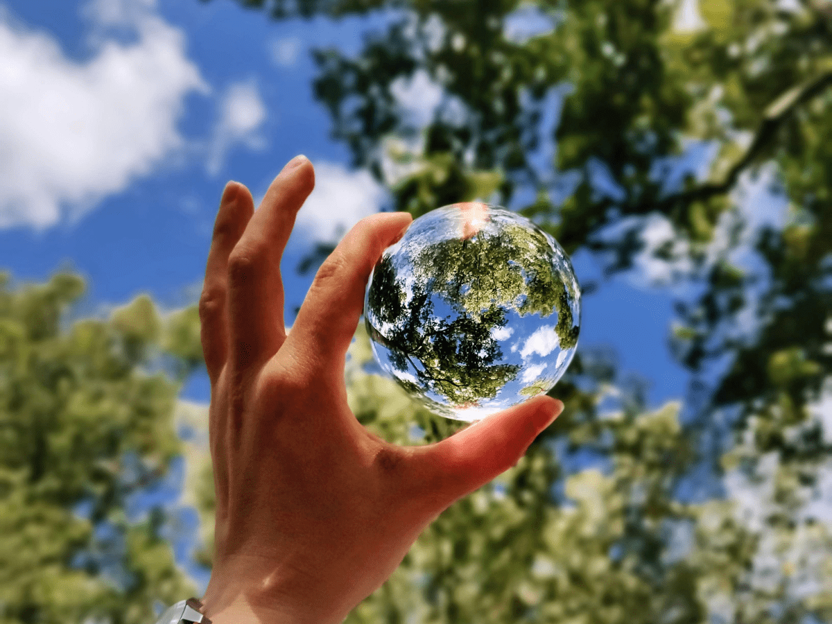 Hand holding glass orb representing sustainability and the Earth.